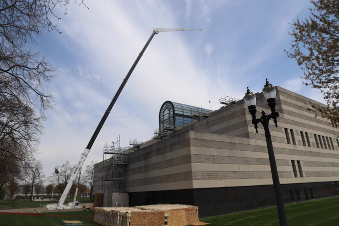 Crain lifting glass to roof of Library of Michigan.