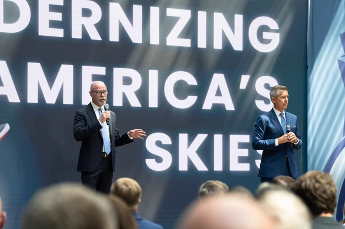 FAA Administrator Bedford and DOT Secretary Sean Duffy stand and speak on stage at the Modern Skies event at DOT headquarters.