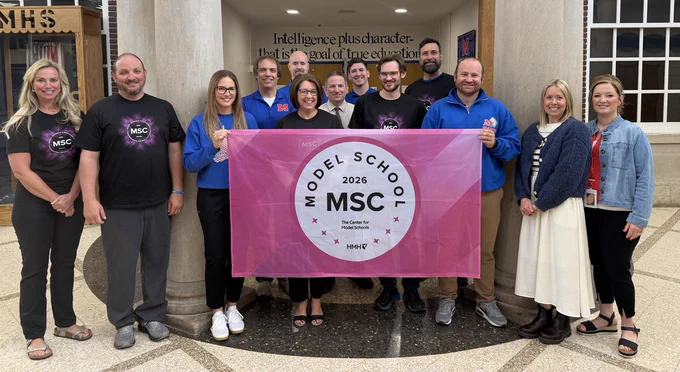 Group of people standing in a large area, holding a sign that says Model School 2026 MSC