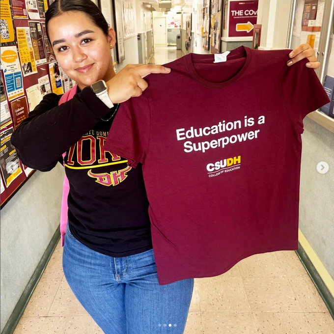 Sabrina holding a burgundy t-shirt that says "Education is a super power"