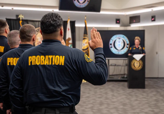 Officers raise their right hands while taking the oath during a swearing-in ceremony led by the Chief Probation Officer.