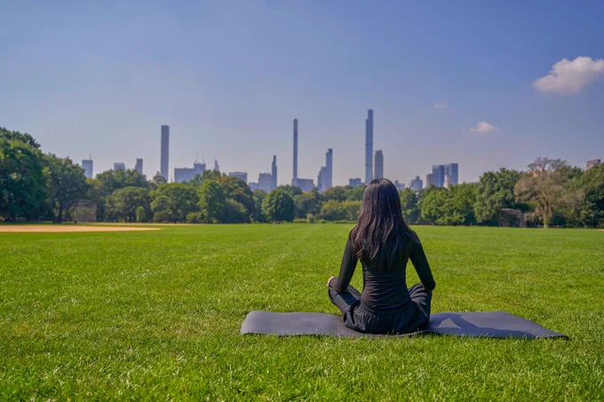 A woman mediating on Central Park's Great Lawn