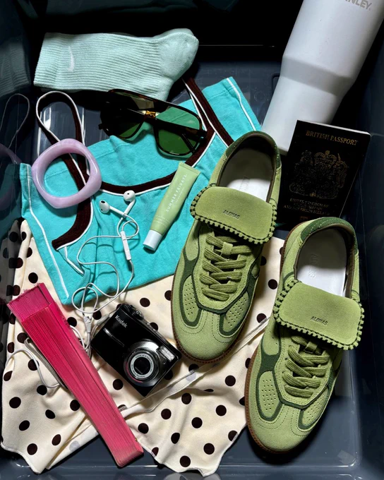 An image of a pair of light green ALOHAS Tb 490 trainers sitting in a black tray surrounded by a digital camera, earphones and accessories.