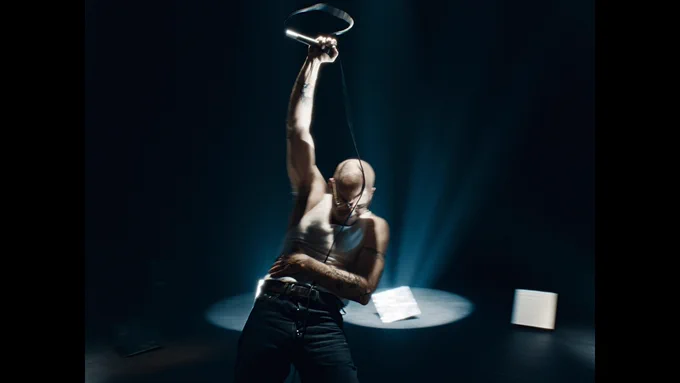 man in darkened room holding microphone in the air.