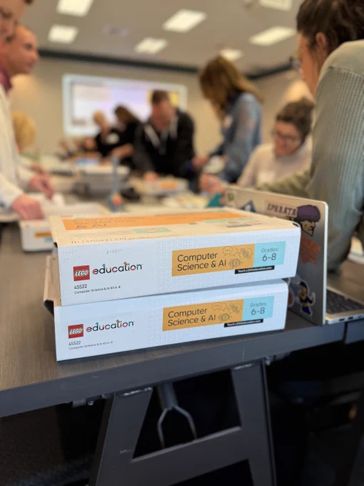 Two LEGO Education kits sitting on a table where adults are working together