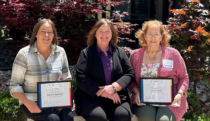 
Pictured L to R: Connie Spencer (winner), Sheila Wunning (Director of DD), Janet Arlen (winner) sitting outside on a bench holding their awards. 