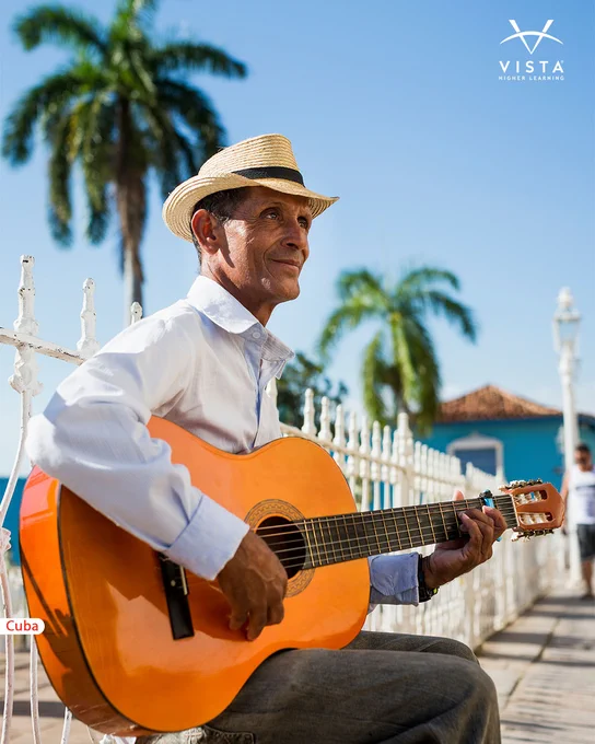 A person wearing a straw hat plays a guitar outdoors, with a backdrop of palm trees and a bright blue sky. A "Cuba" label is visible in the corner, suggesting the location, and the logo "Vista Higher Learning" is in the upper right.