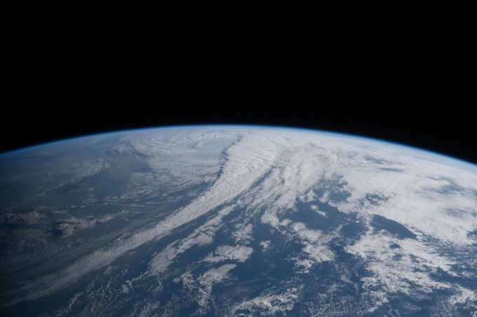Image of Earth from the Artemis II mission. Earth fills the bottom half of the image, its surface covered in blue water and swirling white clouds. Earth\u2019s limb is a blue glow against the curvature of Earth. Credit: NASA