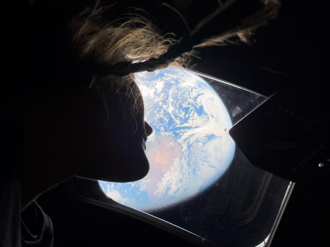 NASA astronaut and Artemis II Mission Specialist Christina Koch peers out of one of the Orion spacecraft’s main cabin windows, looking back at Earth, as the crew travels toward the Moon. Photo credit: NASA.