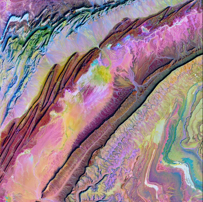 A vibrant abstract landscape with swirling patterns in pink, purple, green, and blue hues resembling geological formations.