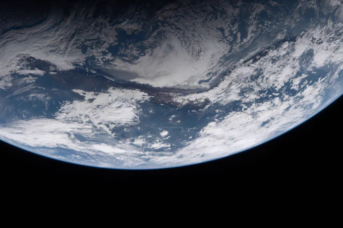 Imagen de la Tierra tomada durante la misión Artemis II. La Tierra ocupa la mitad superior de la imagen. A través de los huecos en la capa de nubes blancas, se pueden ver masas de tierra verdes y marrones, así como agua azul. Crédito: NASA