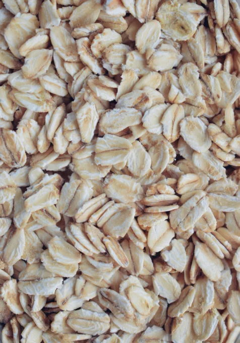 Close-up of dry rolled oats showing their flat, flaky texture and light beige color.