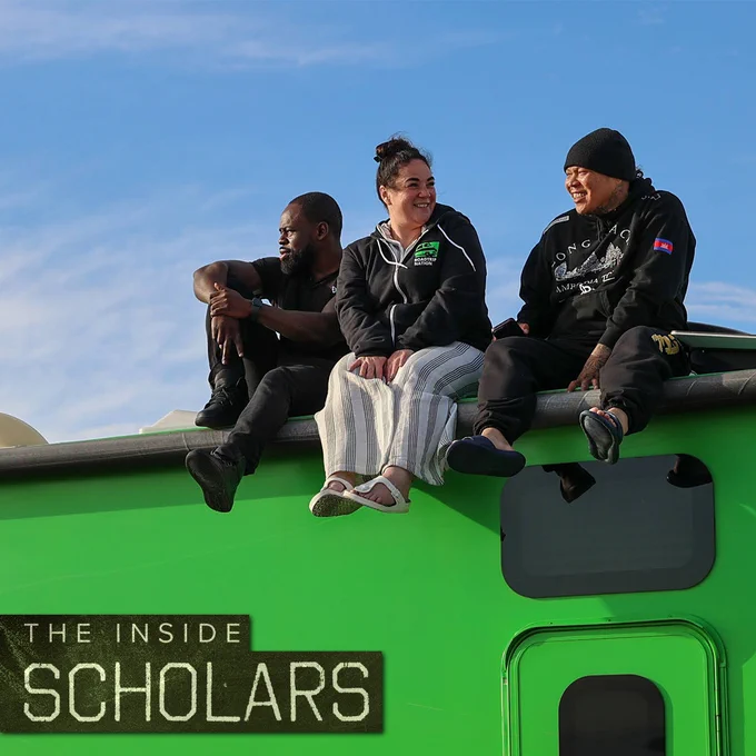 Promotional picture for the film The Inside Scholars featuring three formerly incarcerated scholars sitting on the roof of a structure with a clear blue sky in the background.
