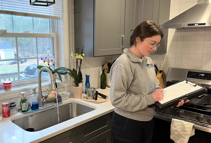 A woman holds a clipboard and fills in a form.