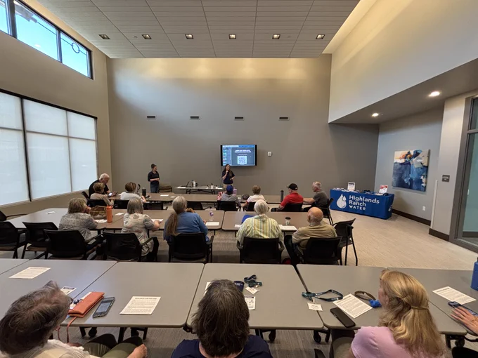 Large room with senior citizens sitting in chairs, facing the front of the room where two woman are hosting a trivia game at the Highlands Ranch Senior Center.