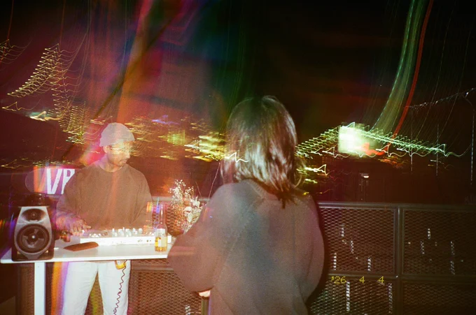 image of 2 people djing on a new york rooftop, shot on film, with heavy light trails.