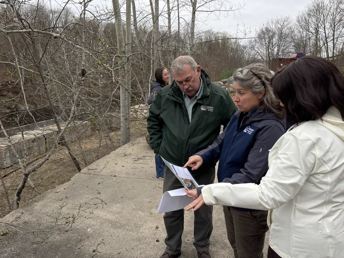 One person pointing to something on a piece of paper and explaining what the paper reads.