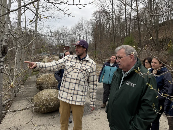 Person pointing to something off camera while small group stands around him and looks.