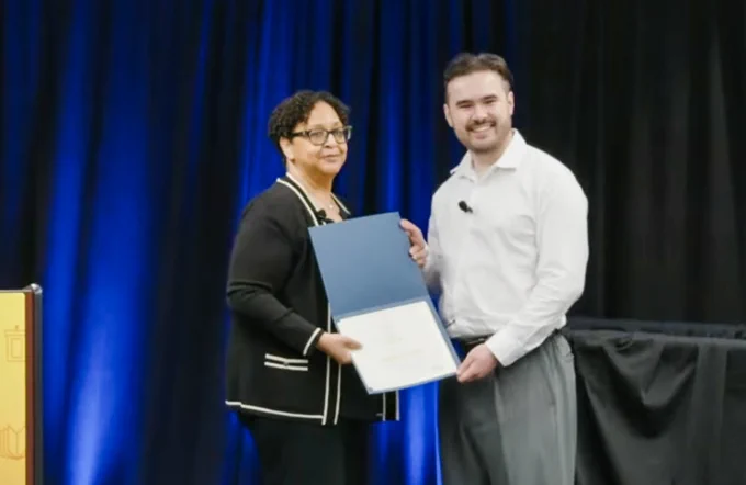 Jack Goon smiling as he receives his UC Grad Slam certificate of participation from UC Vice President, Graduate and Undergraduate Affairs, and Vice Provost, Equity, Diversity and Inclusion, Yvette Gullatt.