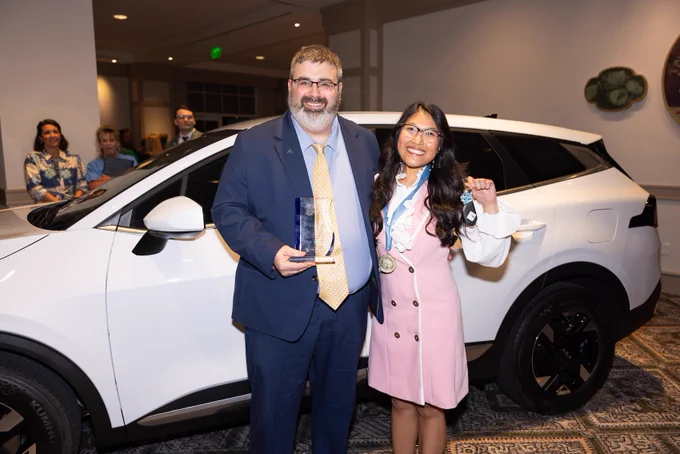 man and woman smiling in front of white Kia sportage car