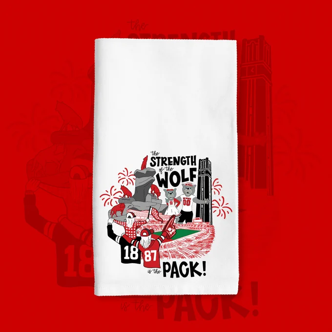 White towel featuring cartoon wolves celebrating with fireworks and a stadium, captioned 'The strength of the wolf is the pack!'