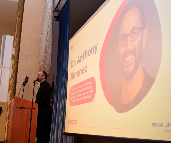 Anthony Jimenez, PhD on stage next to screen.