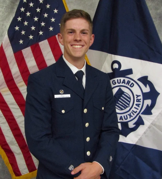 Portrait of a person in uniform in front of the U.S. and coast guard flag