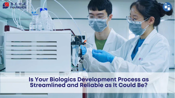 Accelerate Biologics Development with Pharmaron's End-to-End Services. Image of two scientists in a laboratory setting, both wearing lab coats and gloves, working with scientific equipment. The logo and name 'PHARMARON' are displayed in the top left corner, indicating the company associated with the image