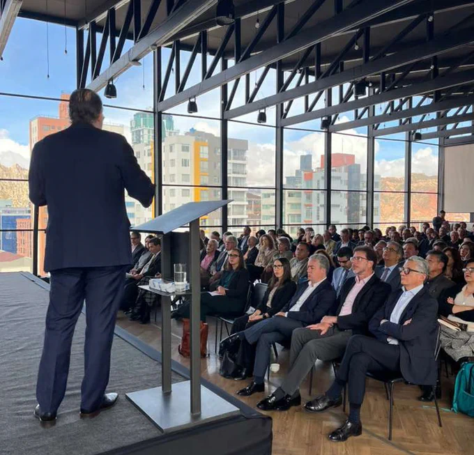 Ricardo Hausmann on stage behind a podium with a room full of people watching his presentation in La Paz, Bolivia. 
