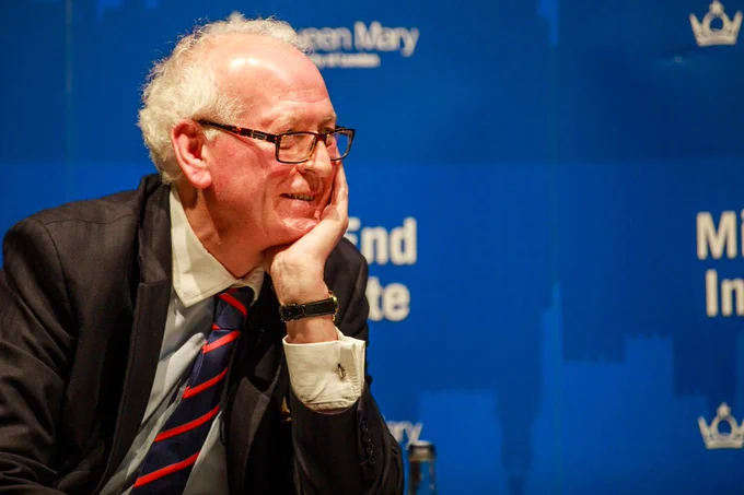 Peter Hennessy at a Mile End Institute event in 2017. He is sitting down, sideways on to the camera, with his hand on his face smiling.