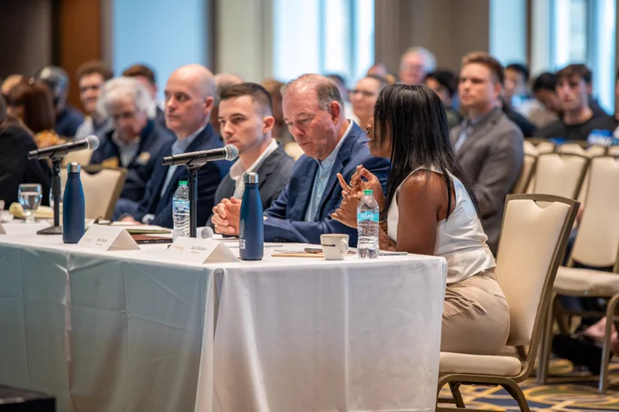 At a long white table, four members sit deep in deliberation.