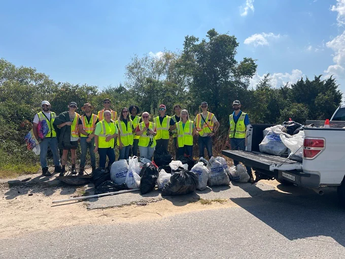 Employees standing in front of garbage bags