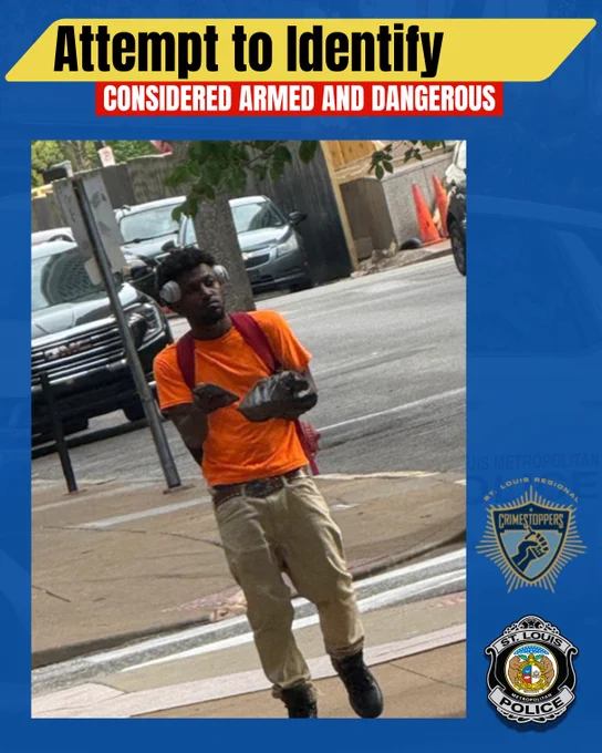 Public safety flyer with the headline "Attempt to Identify" and a red banner reading "Considered Armed and Dangerous."  The central image shows a man walking on a sidewalk. He's described as a black male, medium build, wearing an orange shirt, tan pants, brown studded belt with a large brown buckle, black boots, a red bookbag and white/silver headphones. He is holding an object in both hands. Parked cars, a tree and traffic cones are visible in the background. CrimeStoppers and St. Louis Police logos appear on the right side.
