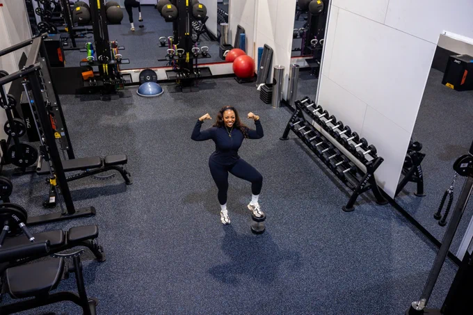 Hatley posing in front of weights at the gym.