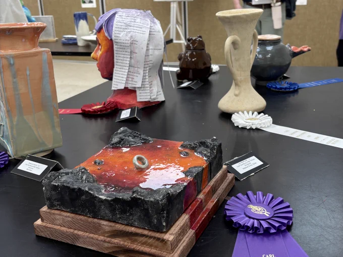 A 1st place blue ribbon winning sculpture with various art sculptures in the background