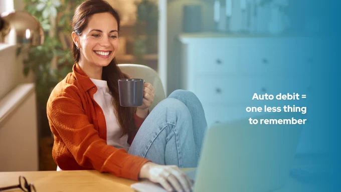 Image of a person using a laptop or phone in a calm, everyday setting (coffee table, desk, etc.). 
Overlay text: 
Auto debit = one less thing to remember
