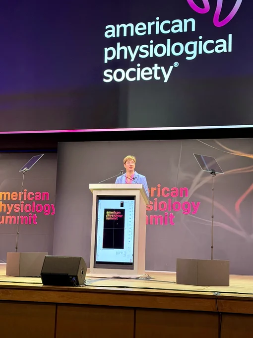Speaker delivering a presentation at the American Physiology Summit behind a podium on stage.