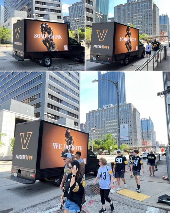 Football fans in Pittsburgh walk past a digital billboard truck showing an advertisement for Vanderbilt University.