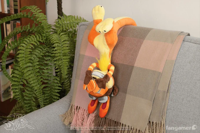 A photo of the Daxter plush posed so that it's hanging from the back of an armchair by its tail, with its hands posed over its eyes. 