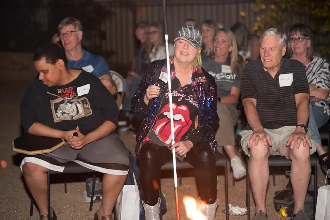 Jamie, Kita with drum on knee, Angie holding white cane, volunteers visible in the background.