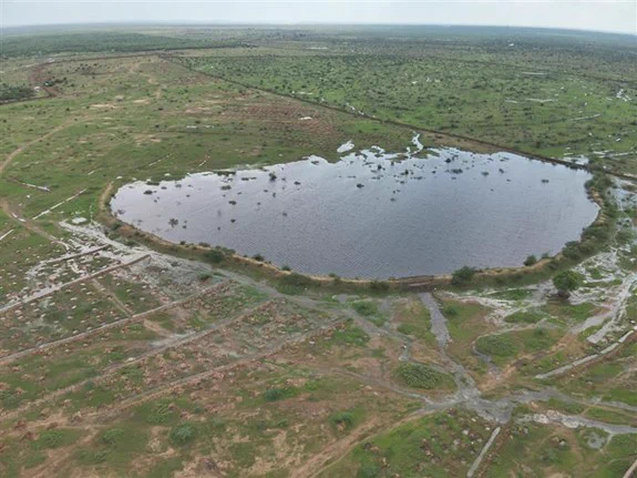 Aerial view of a percolation tank holding water in a semi-arid landscape.