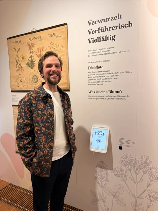 Me standing in a exhibition room of a museum next to an iPad running Art of Flora