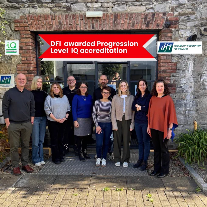The DFI team standing together outside the Disability Federation of Ireland offices, smiling for a group photo. A red banner across the top of the image reads "DFI awarded Progression Level IQ accreditation", with the IQ Progression logo on the left and the Disability Federation of Ireland logo on the right.