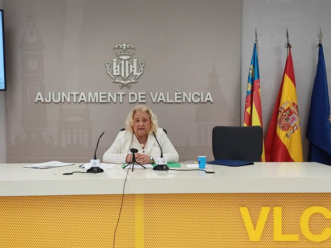 La primera teniente de alcaldía y concejala de Hacienda y  Presupuestos del Ajuntamiento de València durante la rueda de prensa posterior a la Junta de Gobierno Local. Está sentada tras una mesa con micrófonos y banderas (València, España, UE).
