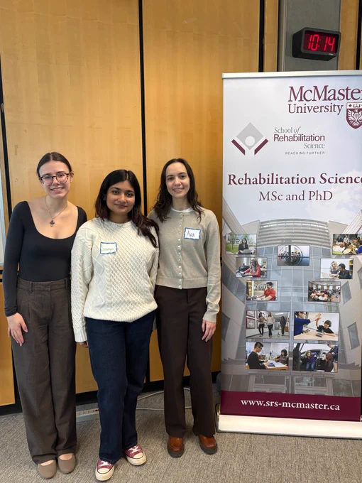 AHA! members Mya (left) Saanya (middle) and Ava (right) standing next to the McMaster Rehab Science banner