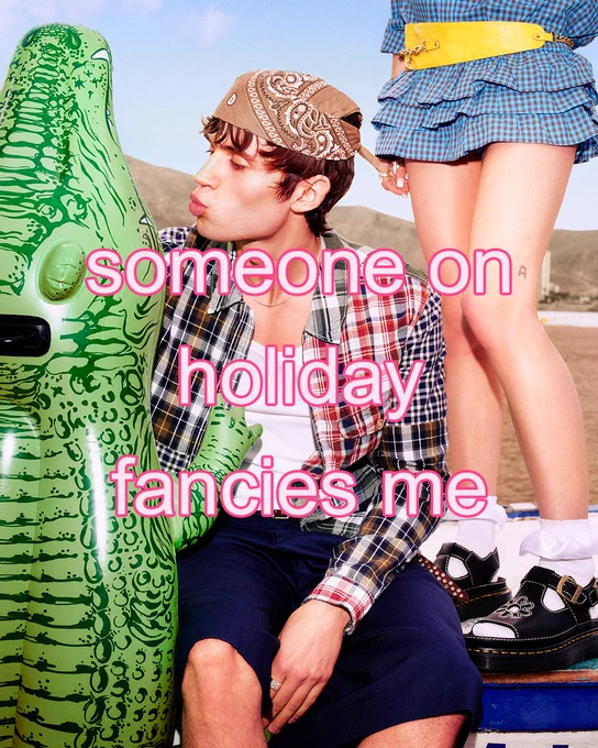 An image of a person sitting next to a pool float on a beach with text overlaying the image saying "someone on holiday fancies me".