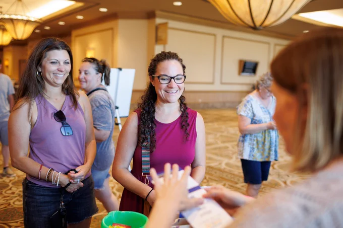 Photo of three people conversing. Two of them are smiling. 