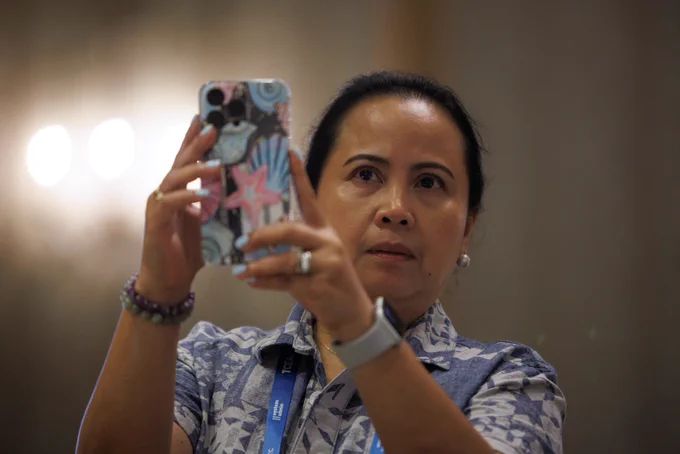 Photo of a person holding their phone up to record or take a photo of something off camera. 