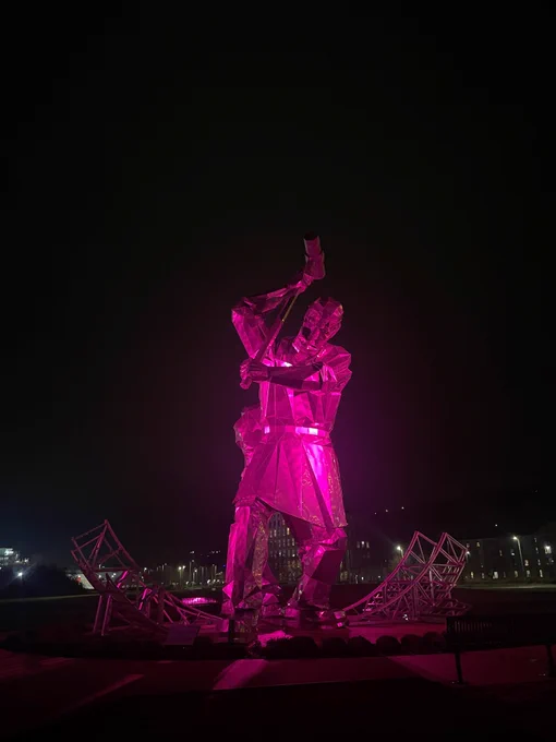 Image of The Shipbuilders of Port Glasgow sculpture lit up pink. 