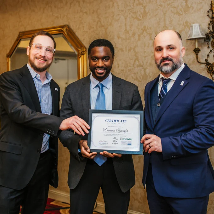 Damena Agonafer receives an award from two men who pose beside him.